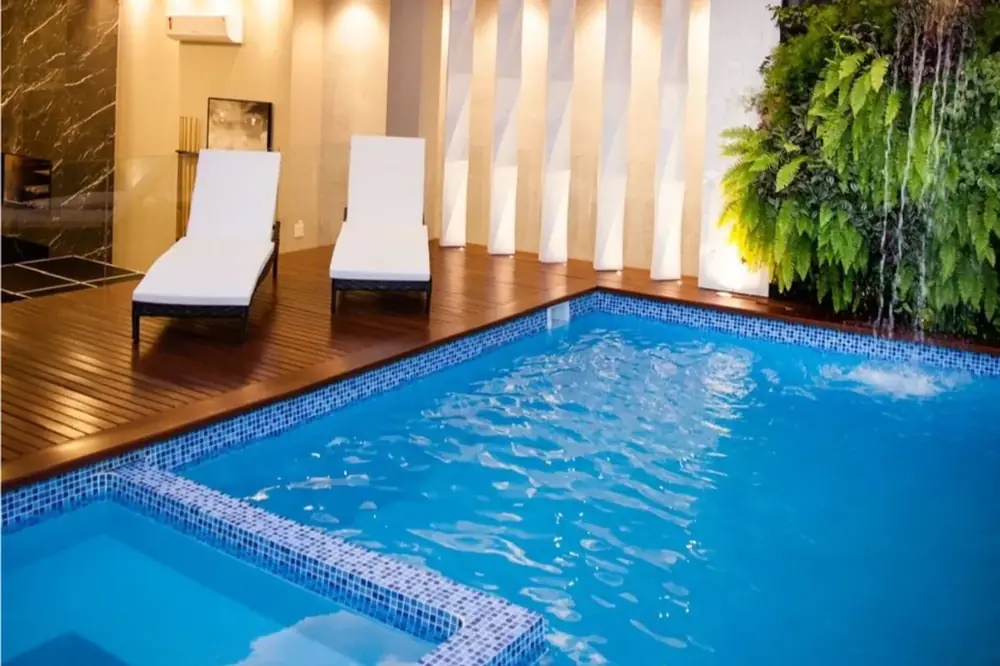 Área interna com espreguiçadeira, em piscina de fibra já instalada